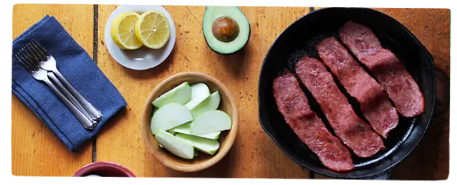 Turkey bacon in a pan next to other ingredients